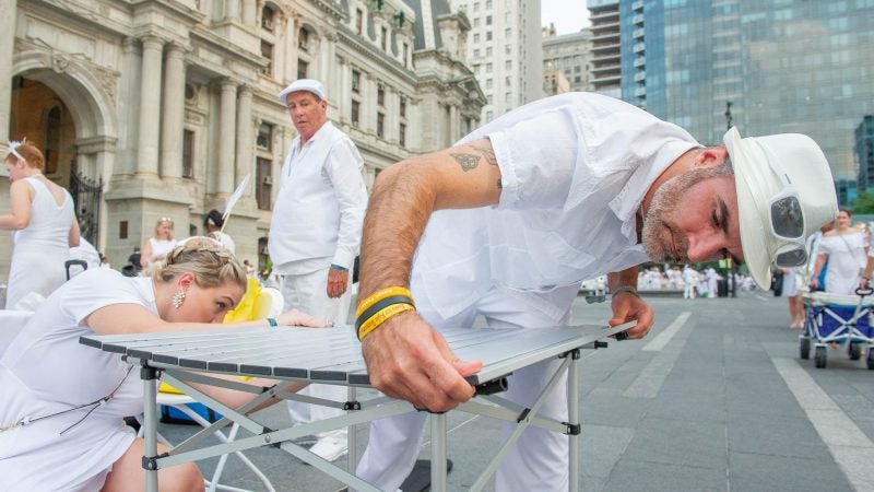 Jarrad Bradt and Taylor Morgis assemble a table at Dilworth Park.(Jonathan Wilson for WHYY)