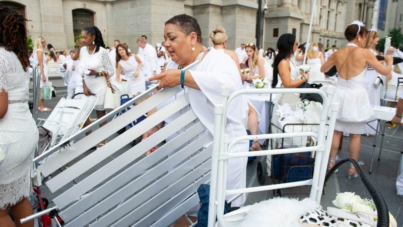 As Diner en Blanc gets underway, Marcia Hinton assembles her table.  (Jonathan Wilson for WHYY)