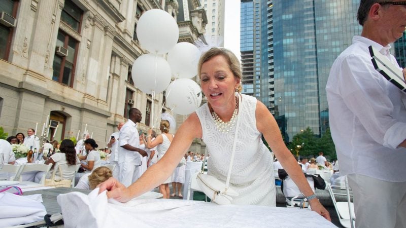 Johnine Meehan spreads a tablecloth at the start of Le Dîner en Blanc. (Jonathan Wilson for WHYY)