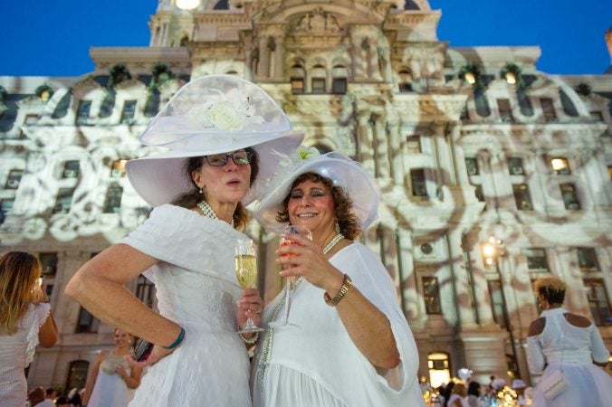Zarbeth Teelucksingh (right) and a friend show off their hats at Le Dîner en Blanc. (Jonathan Wilson for WHYY)