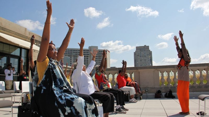 Dr. Robbin Alston leads a seated yoga class on the Terrace of the Free Public Library during Founder's Day, celebrating WURD Radio founder Walter P. Lomax Jr. (Emma Lee/WHYY)
