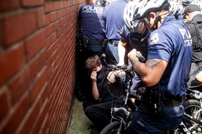 A protestor is brougt down by Philadelphia Police during a scuffle that broke out on Race Street between Antifa protestors and the police. (Brad Larrison for WHYY)