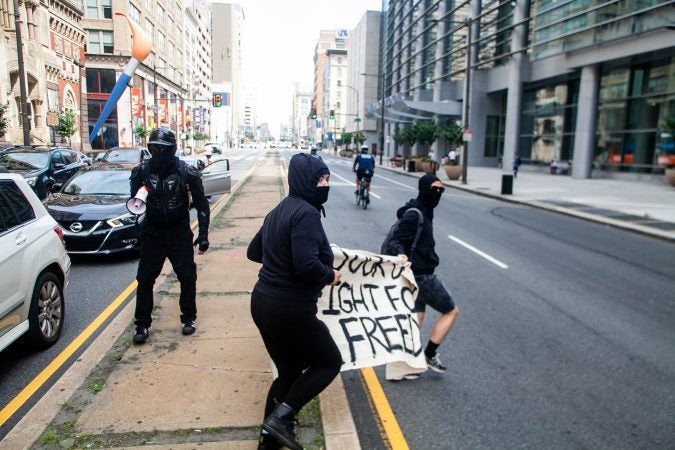 Antifa protestors ran up Broad Street after evading a police blockade in an attempt to intercept a Blue Lives Matter march. (Brad Larrison for WHYY)