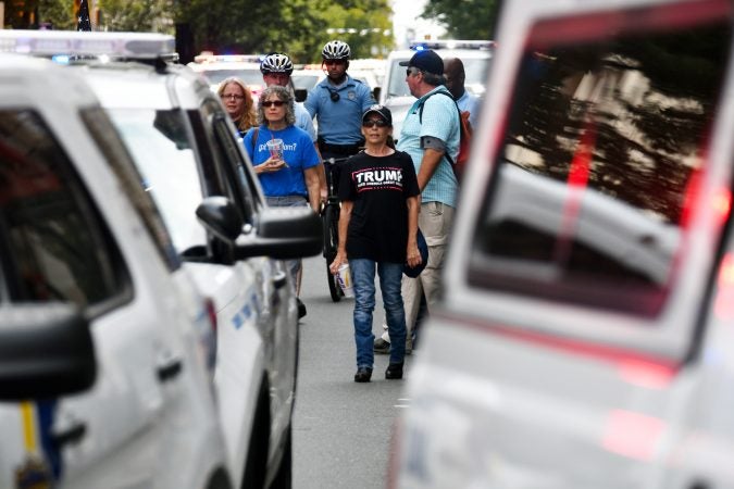 Participants in the Blue Lives Matter march watch from behind police vehicles as a group of counter protestors blocks the path of the march, at Broad and Arch Streets, on  Saturday. (Bastiaan Slabbers for WHYY)