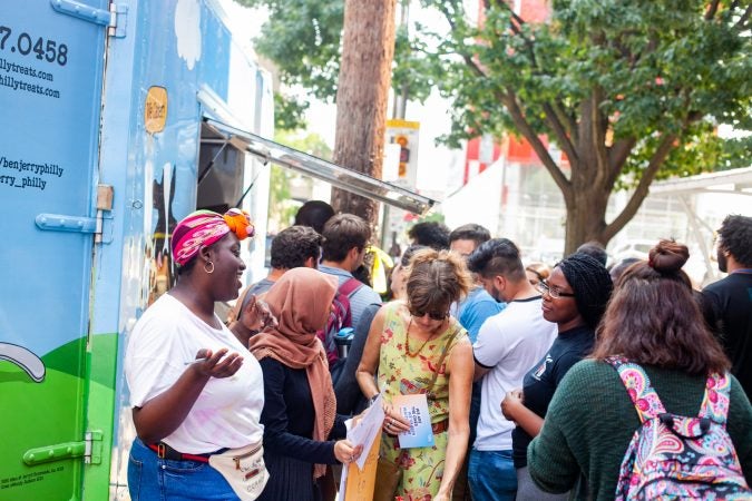 Jodi Risper (left), regional director and organizer with NextGen, asks students at Temple University to fill out a survey in exchange for free Ben & Jerry's ice cream while encouraging them to register to vote. (Brad Larrison for WHYY)