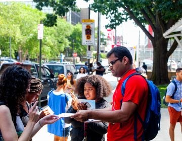 Razin Karu, a Temple University senior and fellow with NextGen, passes out surveys to fellow students that could be redeemed for free ice cream. (Brad Larrison for WHYY)