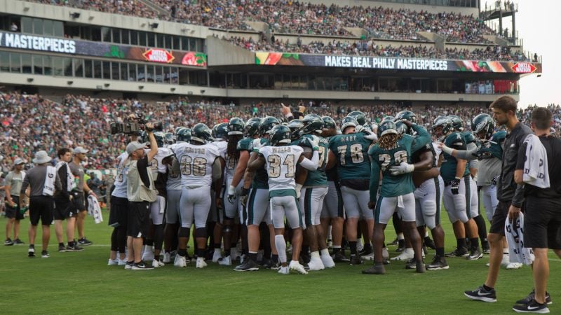 The Philadelphia Eagles huddle at their first open practice of the season Sunday evening. (Kimberly Paynter/WHYY)