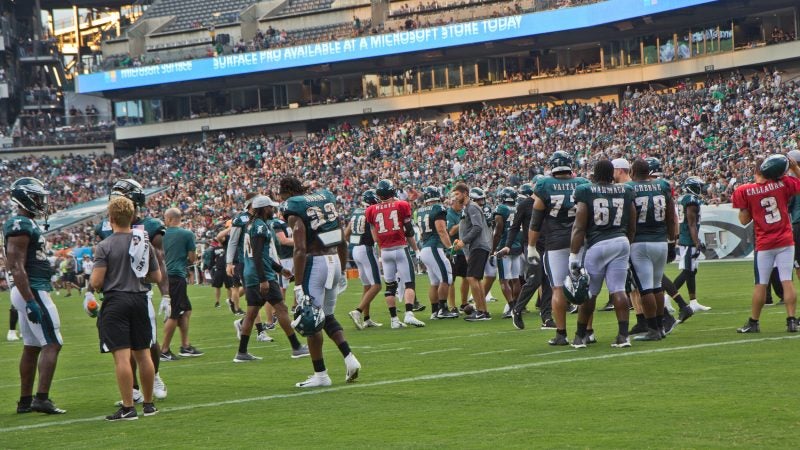 The Philadelphia Eagles huddle during the team's first open practice Sunday evening. (Kimberly Paynter/WHYY)