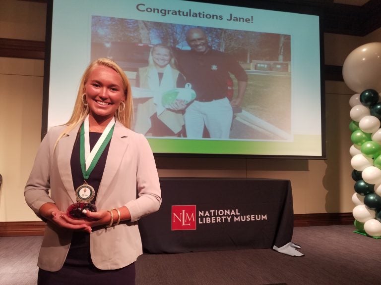 Jane Lyons, with both her Young Hero Award around her neck, and holding her Spark Award, acknowledging her work helping incarcerated youth. (Peter Crimmins/WHYY)