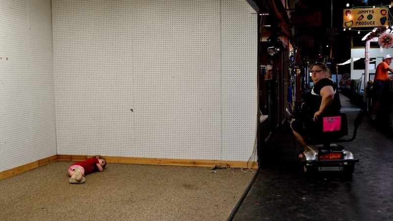 A child takes a break on the floor of an empty stall at Zern's Farmers Market in Gilbertsville, Pa., on Aug. 24, 2018. (Bastiaan Slabbers for WHYY)