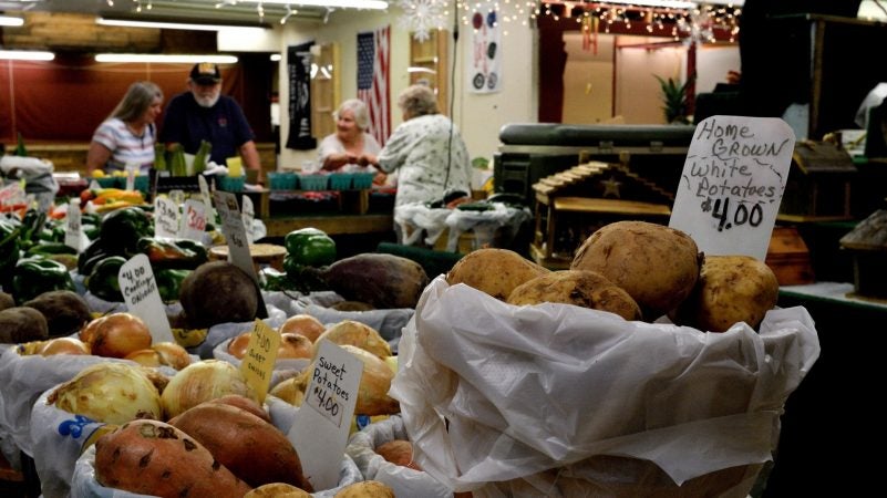 Shoppers chat over the produce for sale at one of the booths at Zern's Farmers Market in Gilbertsville, Pa., on Aug. 24, 2018. (Bastiaan Slabbers for WHYY)