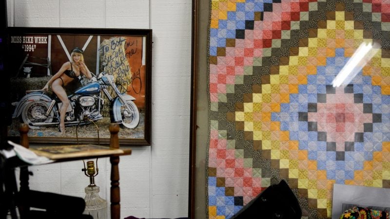 A signed copy of Miss Bike Week 1994 shares a wall with a framed quilt in a booth at Zern's Farmers Market in Gilbertsville, Pa. (Bastiaan Slabbers for WHYY)