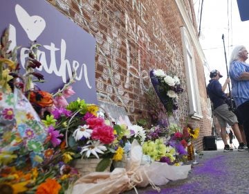 A memorial to Heather Heyer — who was killed at last year's Charlottesville rally by a driver facing murder and hate crime charges — stands at the site of her death. Heyer's mother, Susan Bro, is in the background. (Steve Helber/AP)