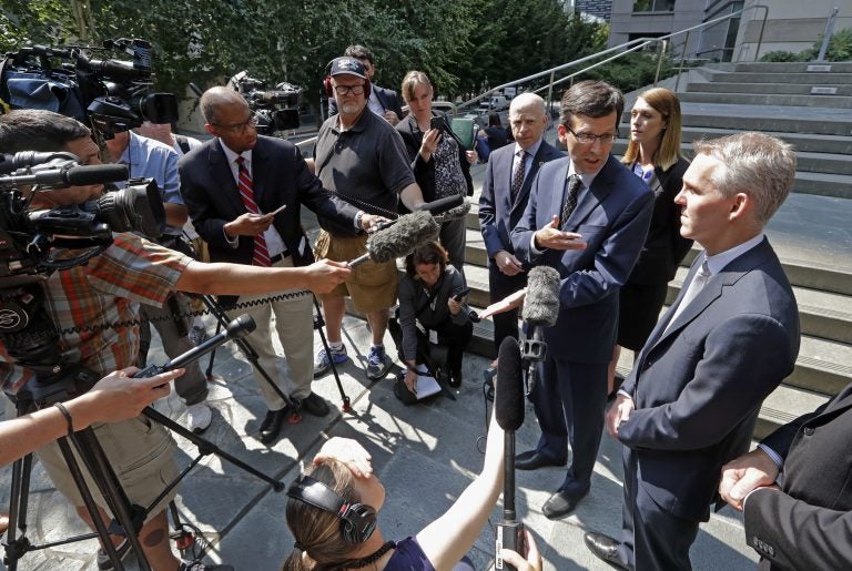 Washington Attorney General Bob Ferguson, third right, speaks with media members following a hearing where a federal judge issued a temporary restraining order to stop the release of blueprints to make untraceable and undetectable 3D-printed plastic guns, Tuesday, July 31, 2018, in Seattle. Ferguson was among eight Democratic attorneys general who filed a lawsuit Monday seeking to block the federal government's settlement with the company that makes the plans available online. They also sought a restraining order, arguing the 3D guns would be a safety risk. (AP Photo/Elaine Thompson)