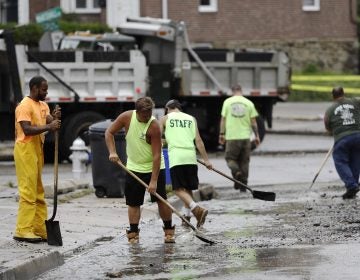 Workers clean up debris swept into the street during flooding in Upper Darby, Pa., Monday, Aug. 13, 2018. Authorities say heavy rains have been causing flooding and prompting road closures and rescues of people from stranded cars in central and southeastern Pennsylvania. (AP Photo/Matt Rourke)