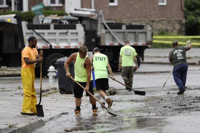 Workers clean up debris swept into the street during flooding in Upper Darby, Pa., Monday, Aug. 13, 2018. Authorities say heavy rains have been causing flooding and prompting road closures and rescues of people from stranded cars in central and southeastern Pennsylvania. (AP Photo/Matt Rourke)