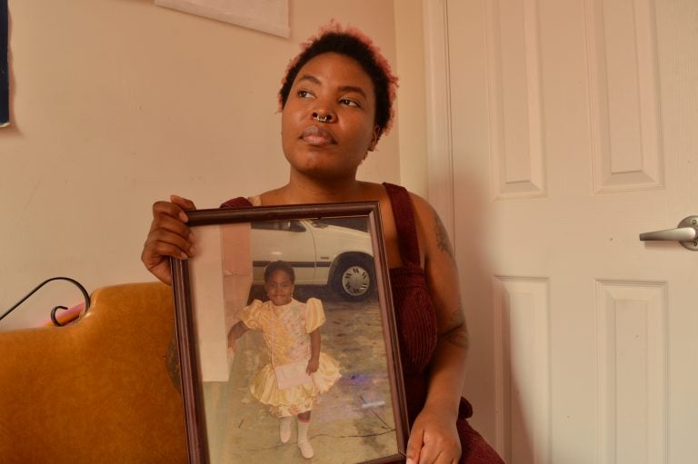 Adesola Ogunleye holds a picture of herself as a young child. She says childhood abuse has played into the anxiety she deals with now, as an adult. (Liz Tung/WHYY)