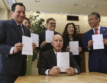 Gov. Jerry Brown holds a copy of a bill to end bail he signed Tuesday, Aug. 28, in Sacramento, Calif. The bill, co-authored by state Sen. Bob Hertzberg, D-Van Nuys, third from right, and Assemblyman Rob Bonta, D-Alameda, right, makes California the first state to eliminate bail for suspects awaiting trial. It goes into effect in October 2019. (Rich Pedroncelli/AP)