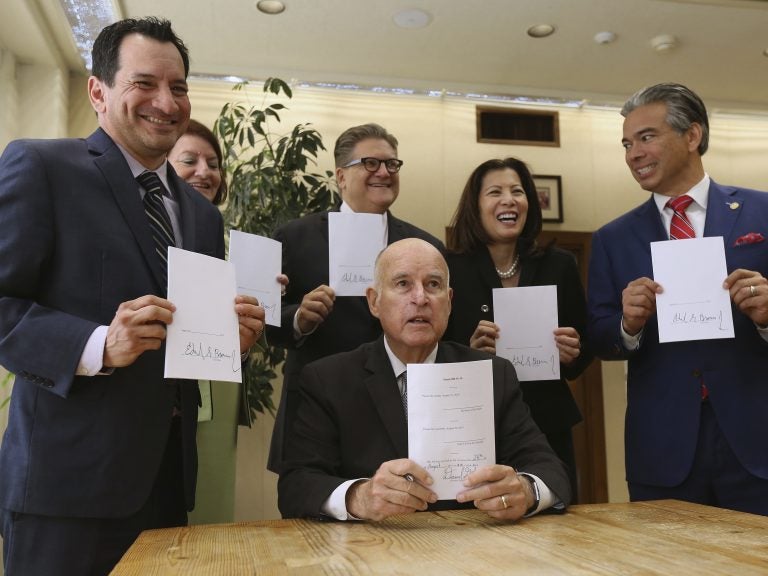 Gov. Jerry Brown holds a copy of a bill to end bail he signed Tuesday, Aug. 28, in Sacramento, Calif. The bill, co-authored by state Sen. Bob Hertzberg, D-Van Nuys, third from right, and Assemblyman Rob Bonta, D-Alameda, right, makes California the first state to eliminate bail for suspects awaiting trial. It goes into effect in October 2019. (Rich Pedroncelli/AP)