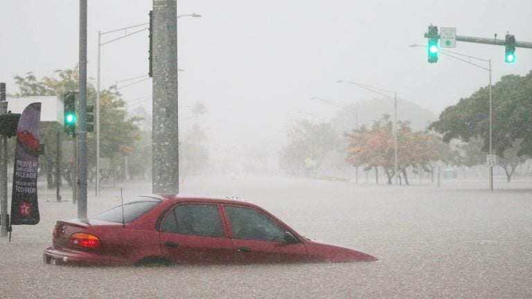 A car is stuck partially submerged in floodwaters from Hurricane Lane rainfall on the Big Island on Wednesday in Hilo, Hawaii.