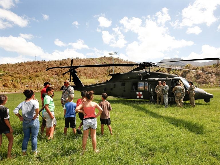 In the mountain town of Juyaya, Puerto Rico, last October, children watched as U.S. Army helicopters brought a team of physicians to assess the medical needs of the local hospital and residents. Going forward, health economists say, the U.S. territory will need continued federal help to deal with its overwhelming Medicaid expenses.
(Carolyn Cole/Los Angeles Times via Getty Images)