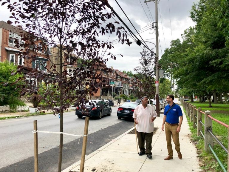 Gregorio Pac Cojulun (left), and Dan Schupsky, an outreach specialist, stroll along one of the new sidewalks. (Meir Rinde/PlanPhilly)