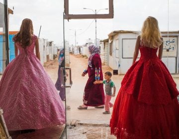 Wedding dresses come in bold hues at Salon Al Fardous — Paradise Salon. The rent-a-gown shop looks out on the temporary housing and makeshift stores in the Zaatari refugee camp in Jordan. (Adib Chowdhury)