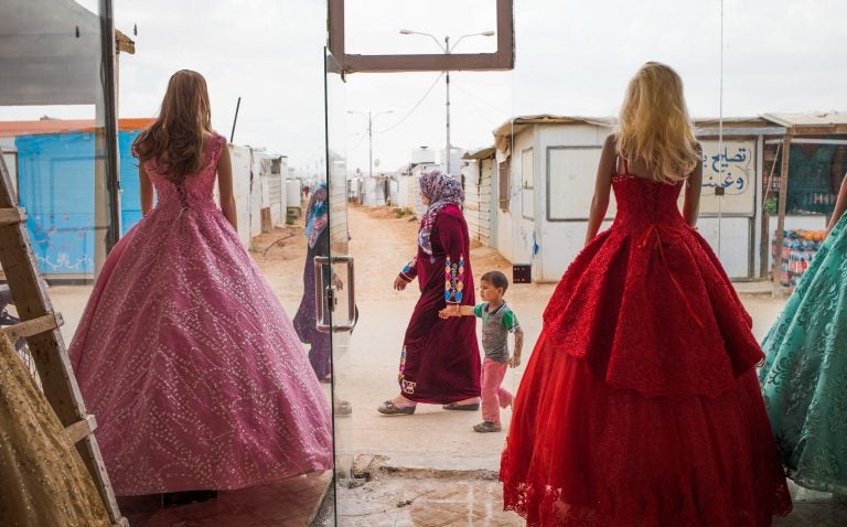 Wedding dresses come in bold hues at Salon Al Fardous — Paradise Salon. The rent-a-gown shop looks out on the temporary housing and makeshift stores in the Zaatari refugee camp in Jordan. (Adib Chowdhury)