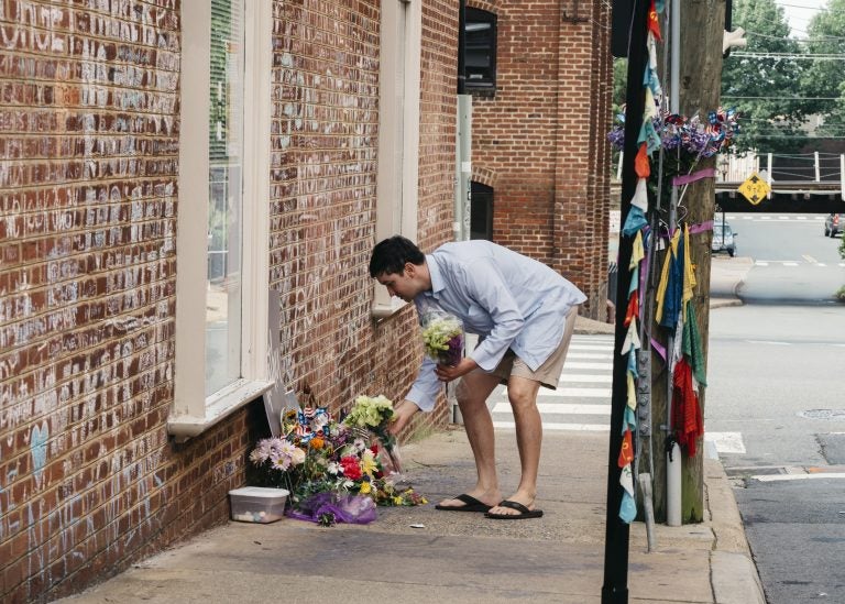 Peter Reijmers, 29, of Charlottesville, lays flowers at a memorial on 4th Street SE where Heather Heyer was killed last August. (Justin T. Gellerson/NPR)