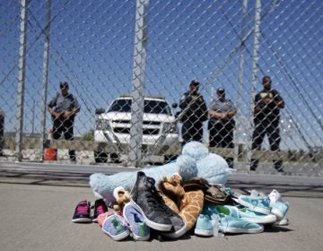 Shoes and a teddy bear, brought by a group of U.S. mayors, are piled up outside a holding facility for immigrant children in Tornillo, Texas, near the Mexican border, Thursday, June 21, 2018.  Mayors from more than a dozen U.S. cities including New York and Los Angeles gathered near the holding facility to call for the immediate reunification of immigrant children with their families.  (AP Photo/Andres Leighton)