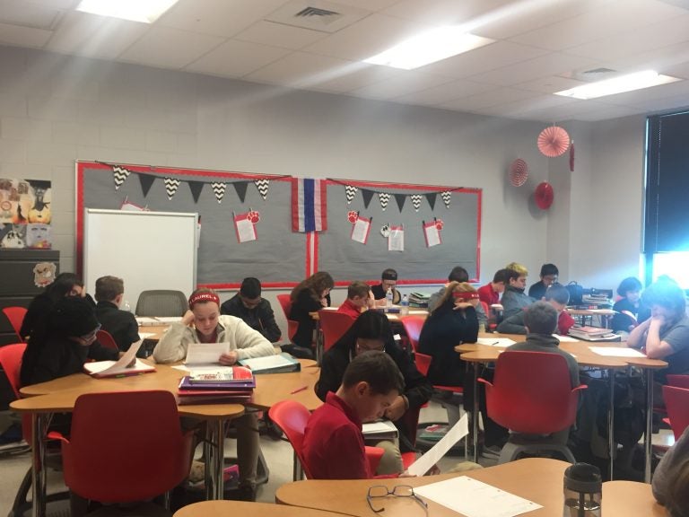 Students in a middle school classroom are seated at desks.