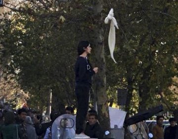 Vida Movahed stands on a telecommunications box, holding a headscarf on a stick in protest against Iran's mandatory hijab rules, in Tehran in December. Since then, Iranians have staged various protests for women's rights. (Abaca Press/Sipa USA via AP)