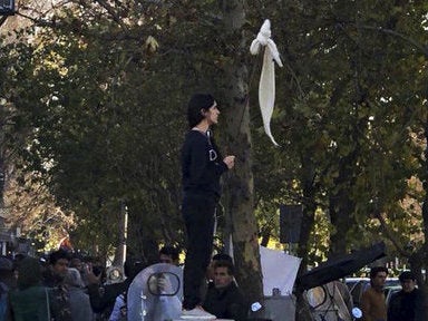 Vida Movahed stands on a telecommunications box, holding a headscarf on a stick in protest against Iran's mandatory hijab rules, in Tehran in December. Since then, Iranians have staged various protests for women's rights. (Abaca Press/Sipa USA via AP)