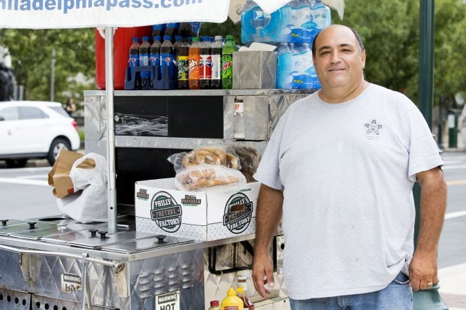 Dominic Mazza, 51, poses with his hot dog stand, Mazza Brothers Hot Dogs, outside of the Franklin Institute on Saturday. A licensed vendor, Mazza says that the vendors selling bottled water without permits 