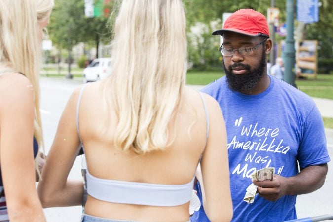 Saadiq Garner, 29, sells bottled water to festival-goers Saturday. Garner's  goal was to make $1,000 from vending water bottles, Gatorade, and rain ponchos. (Rachel Wisniewski for WHYY)