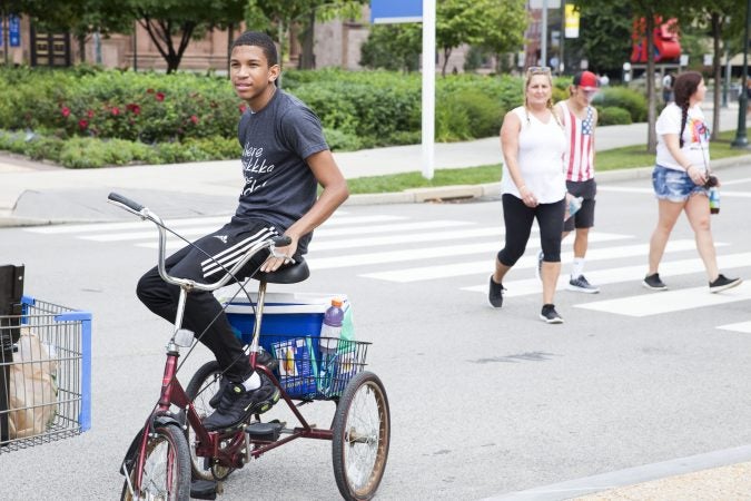 Siddeeq Grady, 16, aids his mentor, Saadiq Garner (not pictured) in selling water bottles to festival-goers Saturday afternoon. (Rachel Wisniewski for WHYY)