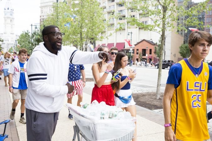 Warren Kale (left) attempts to sell water outside the Made in America festival Saturday. Vending water bottles is currently Kale's primary source of income.  (Rachel Wisniewski for WHYY)