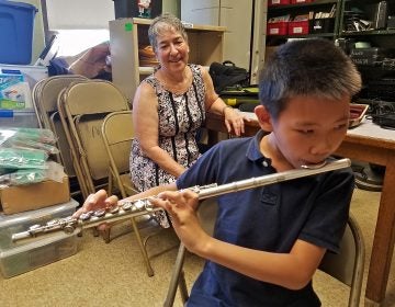 Leo Zhang, a student at Mayfair Elementary, will learn to play on a flute repaired through the Broken Orchestra program. Behind him is Tobie Hoffman, who played the flute in the 