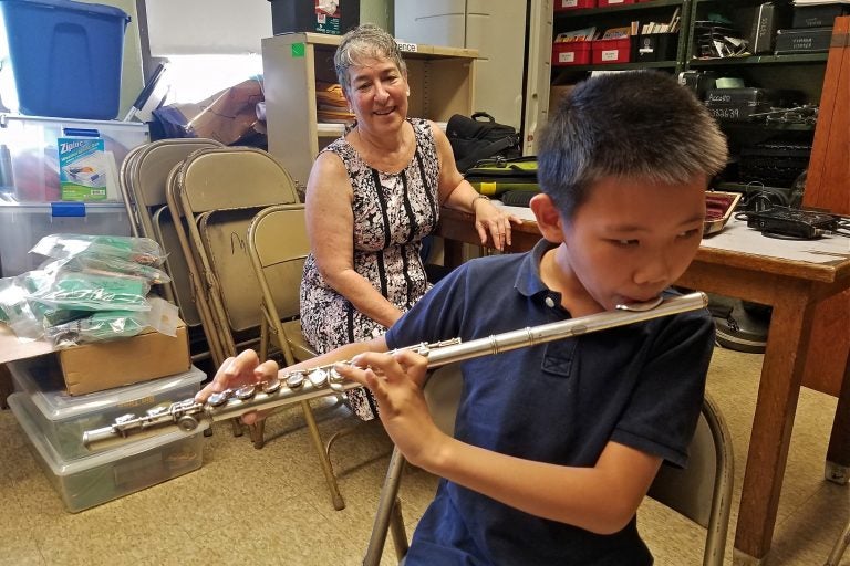 Leo Zhang, a student at Mayfair Elementary, will learn to play on a flute repaired through the Broken Orchestra program. Behind him is Tobie Hoffman, who played the flute in the 