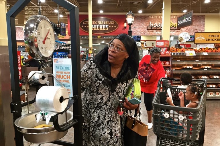 April Ellis weighs some bananas at the Island Avenue Shoprite in Southwest Philadelphia while shopping with her grandchildren,  Kalanni and Shareef. (Avi Wolfman-Arent/WHYY)