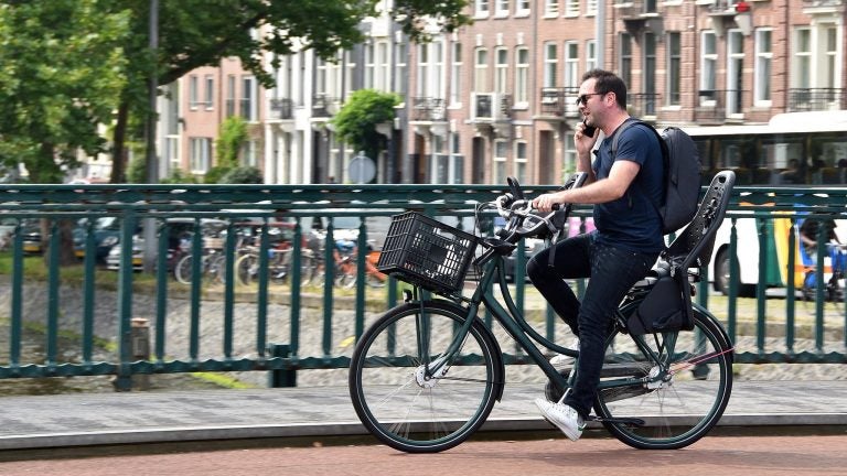 A man talks on the phone while he rides a bike in Amsterdam. Legislation proposed in the Netherlands would impose a fine on bicyclists who use a mobile phone while they're on their bikes.
(FaceMePLS/Flickr)