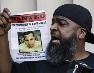 Isaac Gardner speaks while holding up a photo of David Jones