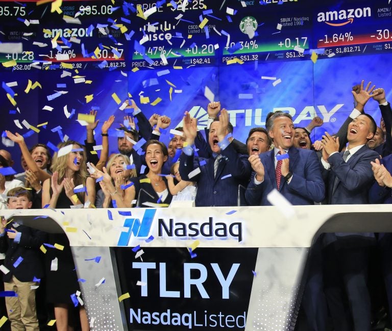 In this July 19, 2018, file photo Brendan Kennedy, (third from right in front), CEO and founder of British Columbia-based Tilray Inc., a major Canadian marijuana grower, leads cheers as confetti falls to celebrate his company's IPO (TLRY) at Nasdaq in New York. Investors are craving marijuana stocks as Canada prepares to legalize pot next month, leading to giant gains for Canada-based companies listed on U.S. exchanges. (Bebeto Matthews/AP Photo, File)