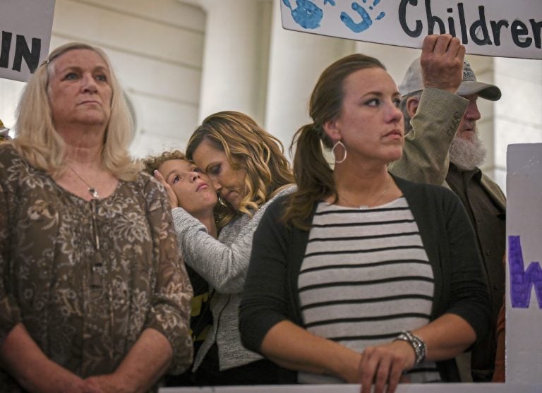 Carolyn Fortney, center, hugs her son Elias, 11, during a press conference in the state Capitol Building on Monday, Sept. 24, 2018, in support of legislation that would change the statute of limitations for child sex crimes. Carolyn is one of five sisters in the Fortney family to suffer from abuse by a priest. Others in the photograph are Judy Deaven, left, whose son Joey Behe was abused by a priest and died of an overdose in 2015; Carolyn's sister Patty Fortney-Julius, i stripped shirt, who was also abused, and the sisters' father, Edward Fortney, right. (Steve Mellon/Pittsburgh Post-Gazette via AP)