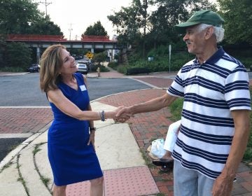 Kathy Jennings, who won Thursday's Democratic primary for attorney general, shakes hands with a voter about 6:30 p.m.  outside Lincoln Towers apartments in Wilmington's Trolley Square neighborhood. (Cris Barrish/WHYY News)