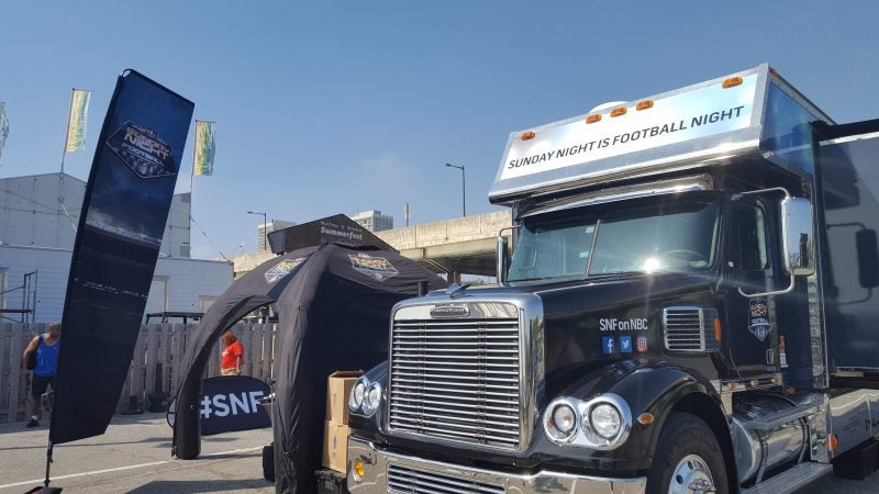 Workers set up for the NFL Kickoff Experience at Penn's Landing, leading into the Eagles' home opener Thursday evening. (Sara Hoover for WHYY)