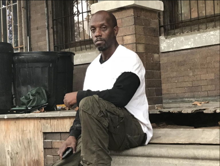 Derrick Eberhart, whose brother was murdered, sits  on his front porch in Nicetown (Philadelphia Tribune/John Mitchell)