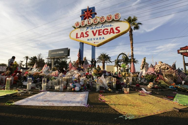 People visit a makeshift memorial for victims of the mass shooting in Las Vegas in October 2017. Fifty-eight crosses were planted in front of the sign to commemorate each of the people killed in the attack. (John Locher/AP)