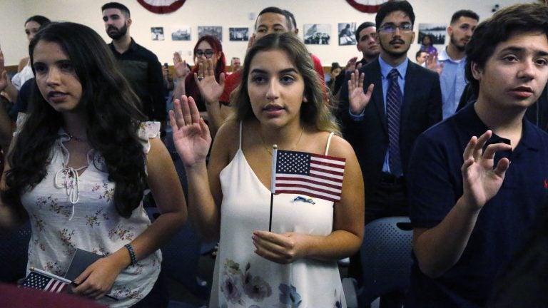 Ericka Ames, center, of Nicaragua recites the Oath of Allegiance during a naturalization ceremony at the U.S. Citizenship and Immigration Services in Miami. The backlog of citizenship applications has increased dramatically under the Trump administration. (Wilfredo Lee/AP)