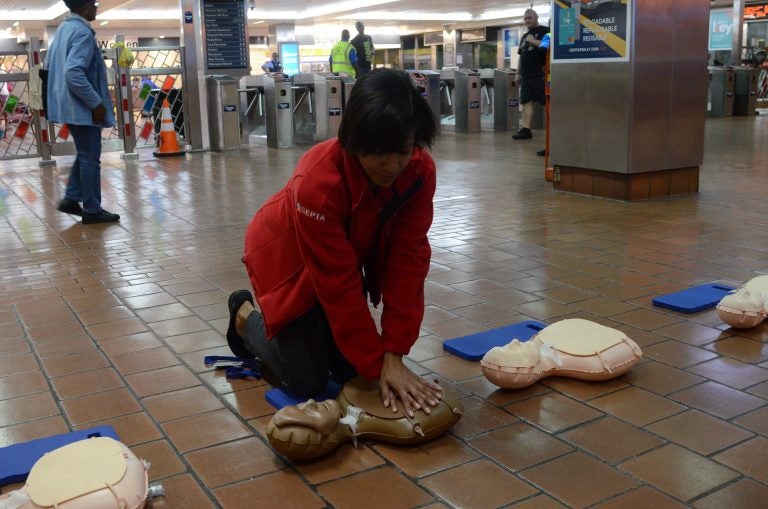 SEPTA Ambassador Carrie Givhan demonstrates CPR on a dummy at Jefferson Station. (Tom MacDonald/WHYY)